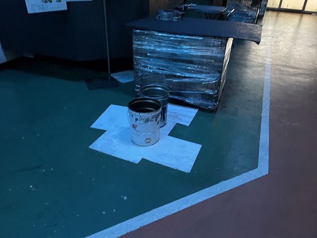 工場の雨漏りをバケツで受けている写真