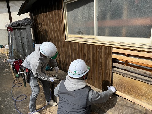 福山市にて蔵の波板トタン外壁とはみ出した瓦屋根の改修工事新しい外壁材ヨドコウのヨドプリントを垂直プラ連結釘リング釘で張る作業風景