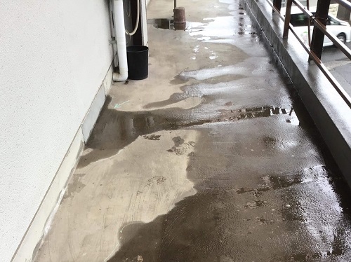 福山市で水捌けの悪い外廊下床を防滑性ビニル床シート補修工事前の水が廊下に溜まっている様子